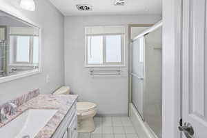 Full bath with vanity, shower / bath combination with glass door, and light tile patterned flooring