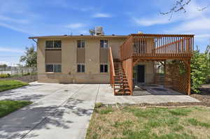 Back of house with brick siding, a wooden deck, and a patio area