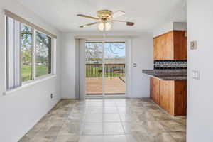 Unfurnished dining area featuring ceiling fan, light tile patterned flooring, and a textured ceiling