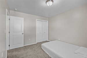 Bedroom with light colored carpet and a closet