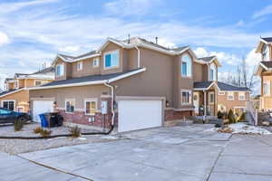 Traditional-style house featuring brick siding, concrete driveway, stucco siding, and an attached garage