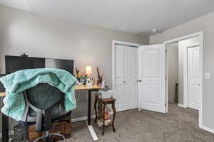 Office area featuring dark colored carpet and baseboards