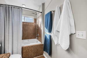 Full bathroom featuring toilet and shower / bath combination with curtain