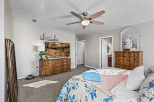 Carpeted bedroom featuring ceiling fan and ensuite bathroom