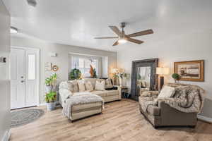 Living room featuring light wood-type flooring, ceiling fan, and a textured ceiling