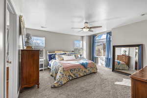 Carpeted bedroom with ceiling fan and a textured ceiling
