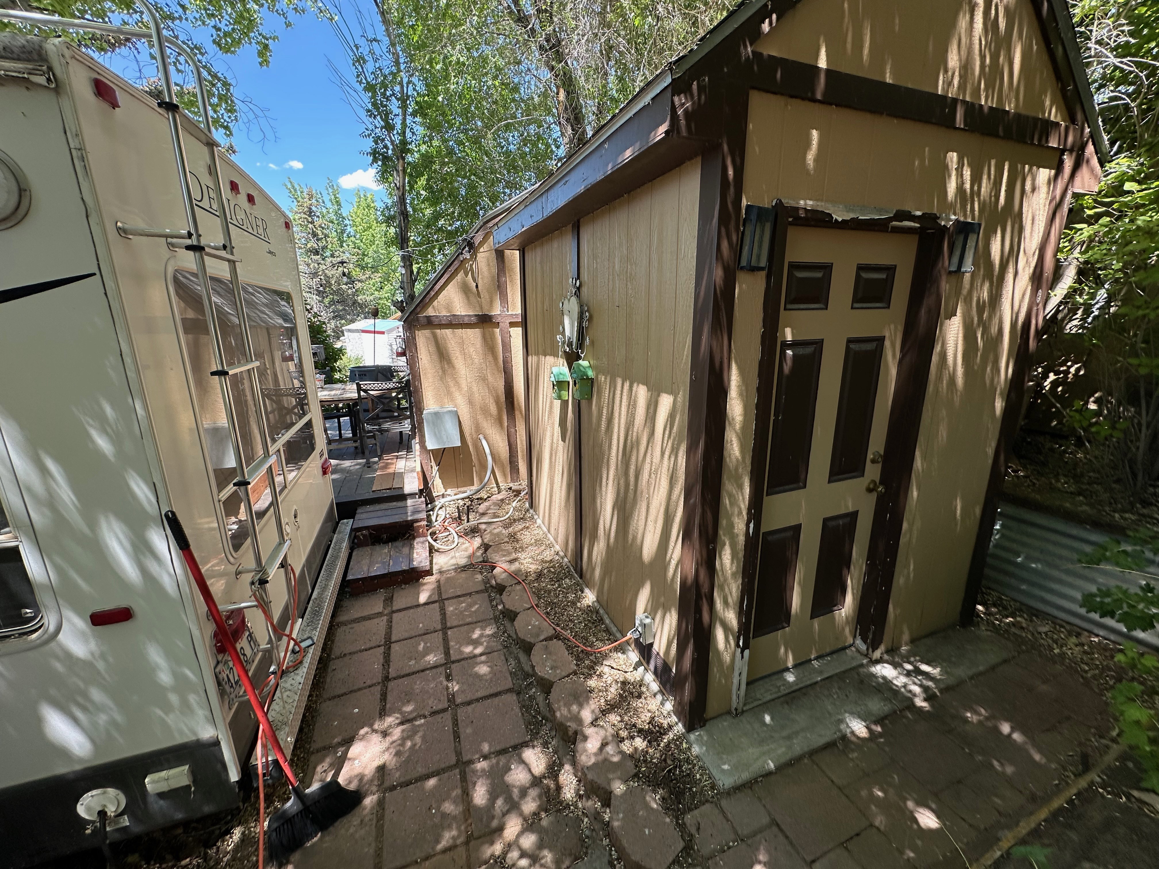 Wood-sided storage shed with a paneled door and dual exterior wall sconces
