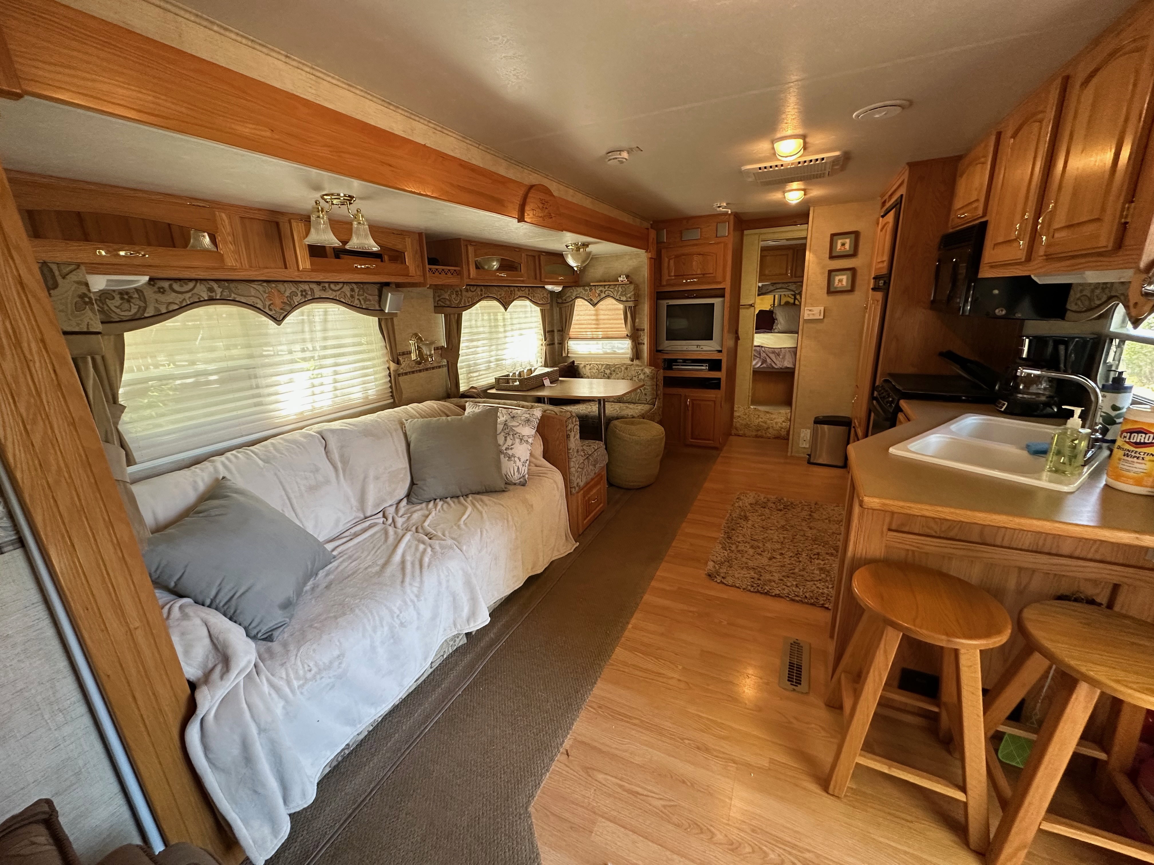 Interior featuring extensive wood-finish cabinetry, built-in dinette, integrated kitchen sink, wood-finish flooring, and multiple windows with blinds