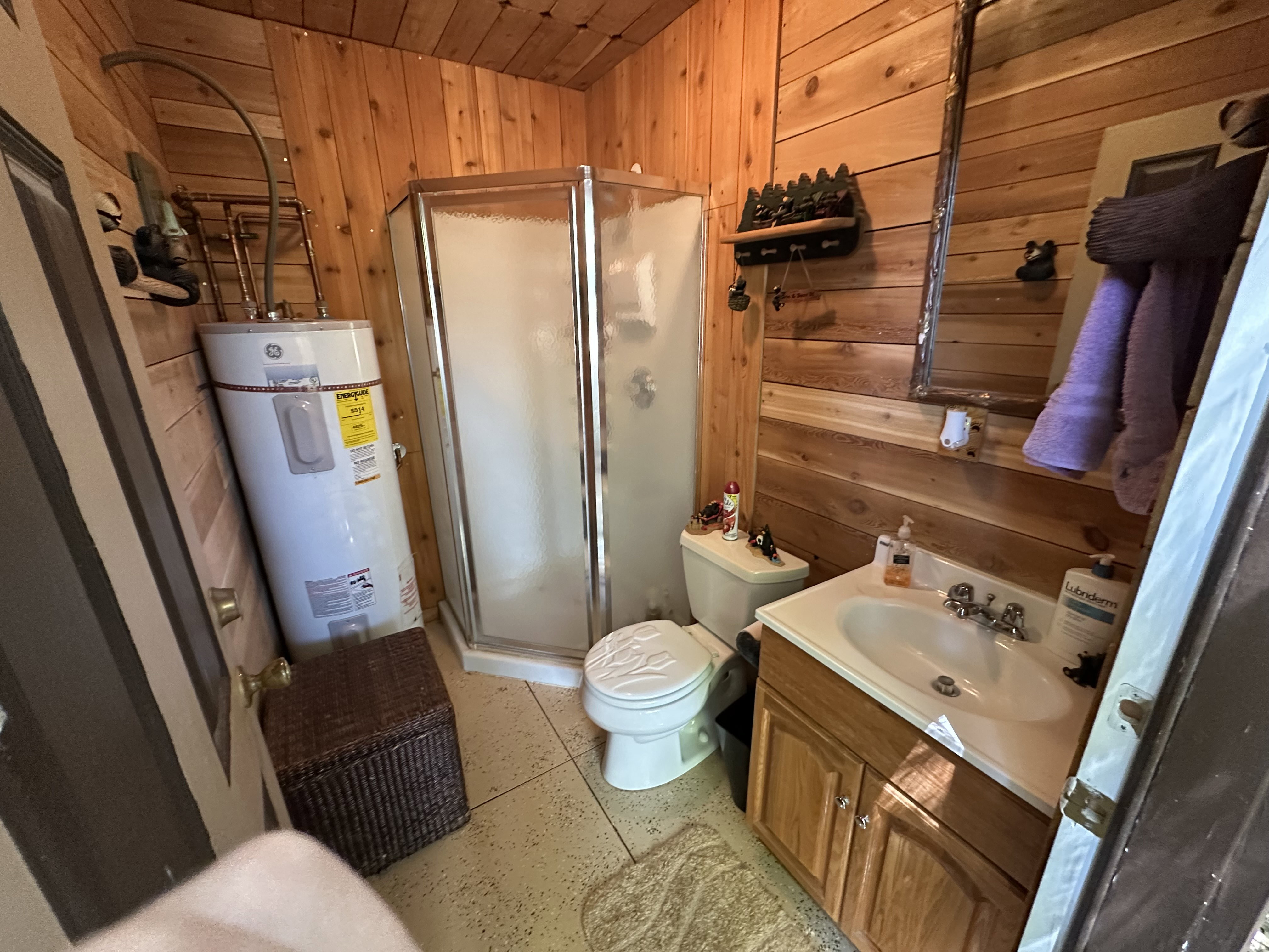 Bathroom with wood walls, a stall shower, vanity, electric water heater, and wooden ceiling