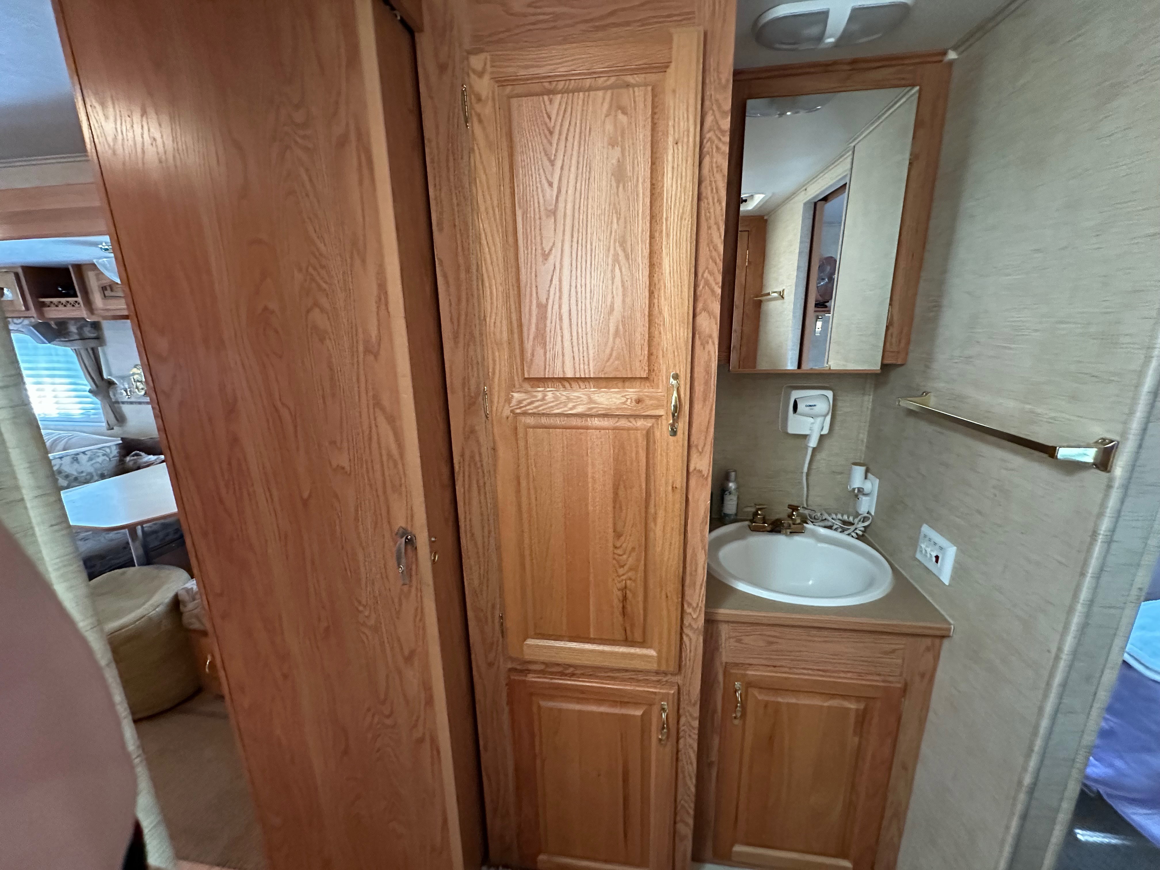 Compact bathroom with wood-finish cabinetry, a built-in sink, and a mirrored medicine cabinet