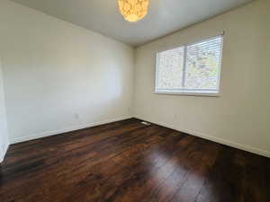 Empty room with dark wood-style flooring and baseboards