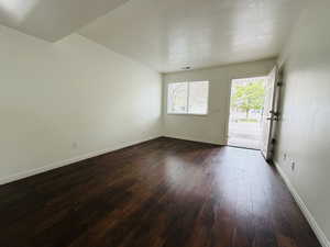 Unfurnished room featuring dark wood finished floors and a textured ceiling
