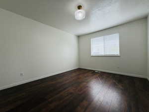 Spare room with dark wood finished floors and baseboards