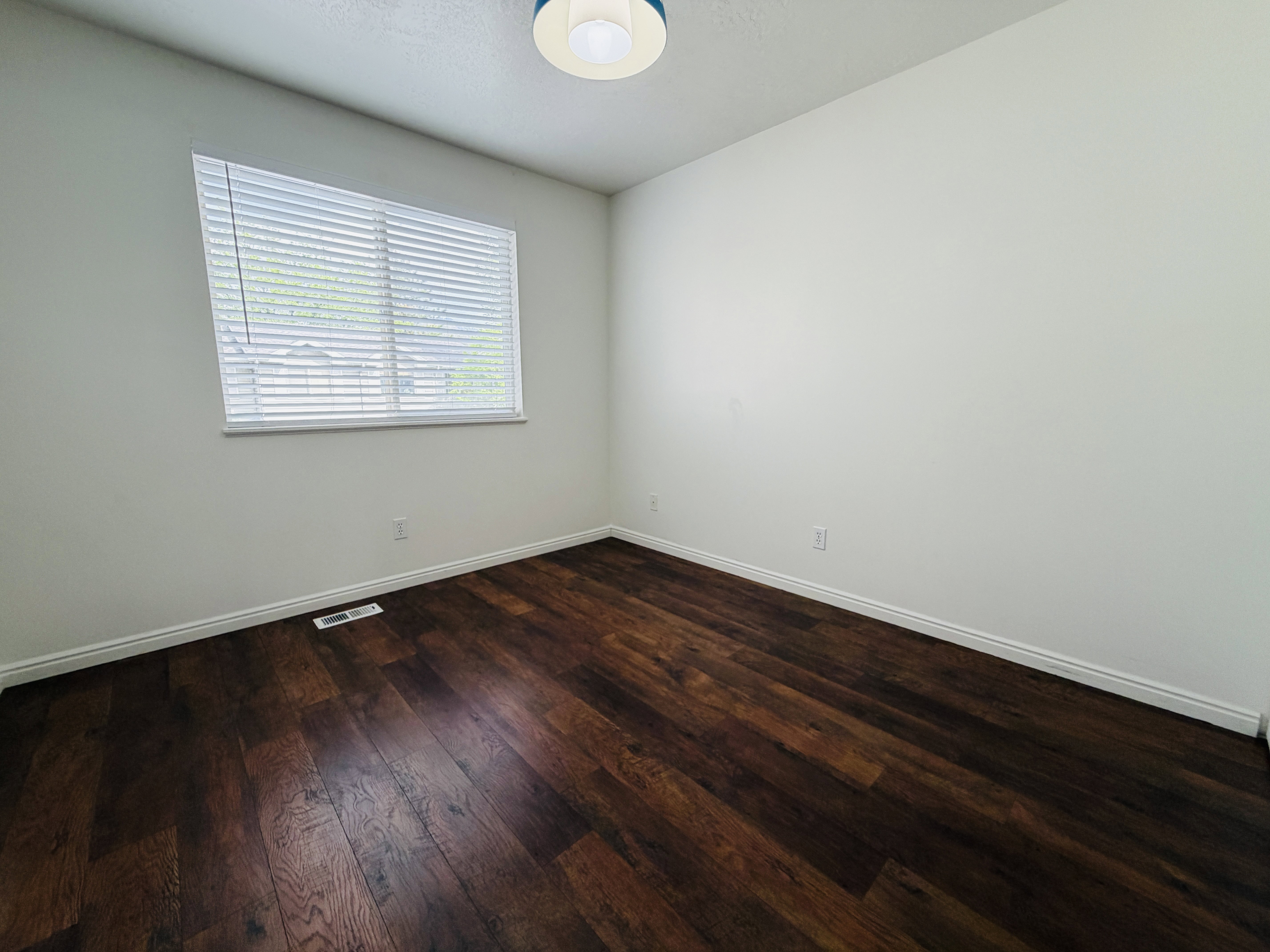 Empty room featuring dark wood finished floors and baseboards