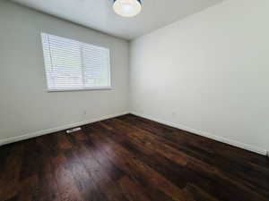 Empty room featuring dark wood finished floors and baseboards