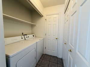 Laundry area featuring washer and dryer and dark tile patterned flooring