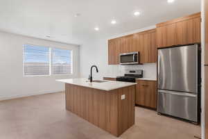 Kitchen featuring stainless steel appliances, modern cabinets, light stone countertops, a kitchen island with sink, and recessed lighting