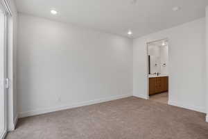 Unfurnished bedroom featuring light carpet, recessed lighting, and ensuite bath