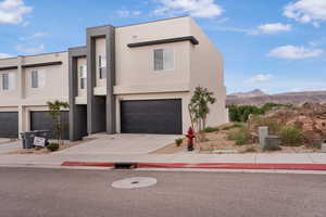 Contemporary home featuring an attached garage, stucco siding, concrete driveway, and a mountain view