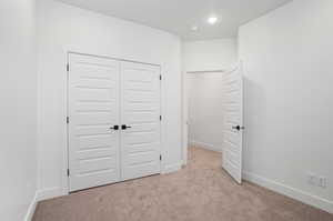 Unfurnished bedroom featuring a closet and light colored carpet