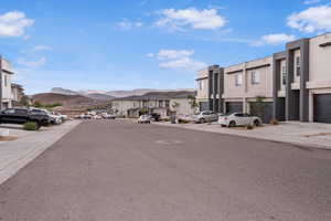 View of asphalt street featuring a residential view, sidewalks, a mountain view, and curbs