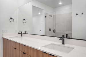 Bathroom featuring a shower stall and double vanity