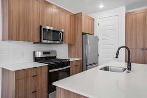 Kitchen featuring modern cabinets, stainless steel appliances, light stone countertops, and recessed lighting