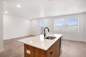 Kitchen with wood finish cabinetry, modern cabinets, an island with sink, healthy amount of natural light, and recessed lighting