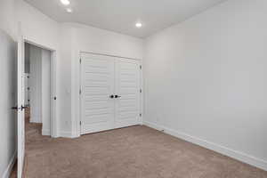 Unfurnished bedroom with carpet, a closet, and recessed lighting