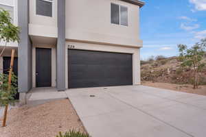 View of front of house featuring stucco siding, an attached garage, and concrete driveway