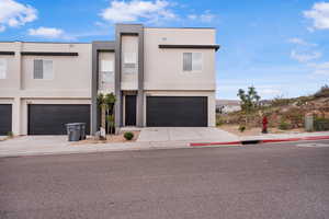 Contemporary house with stucco siding, an attached garage, and concrete driveway