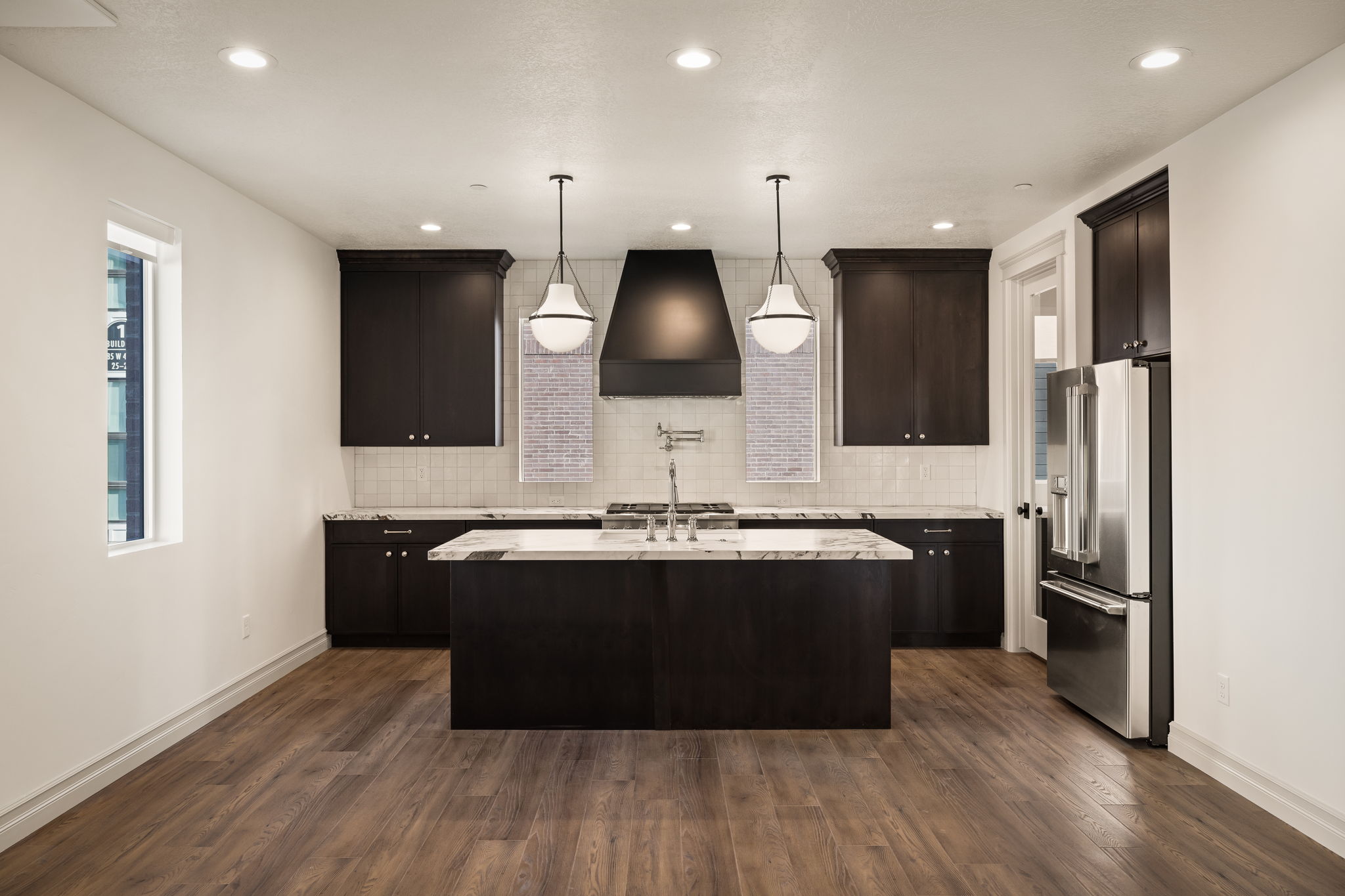Pictures of an exterior unit - Kitchen featuring dark wood finish cabinets, high quality fridge, a center island with sink, light stone countertops, and dark wood finished floors