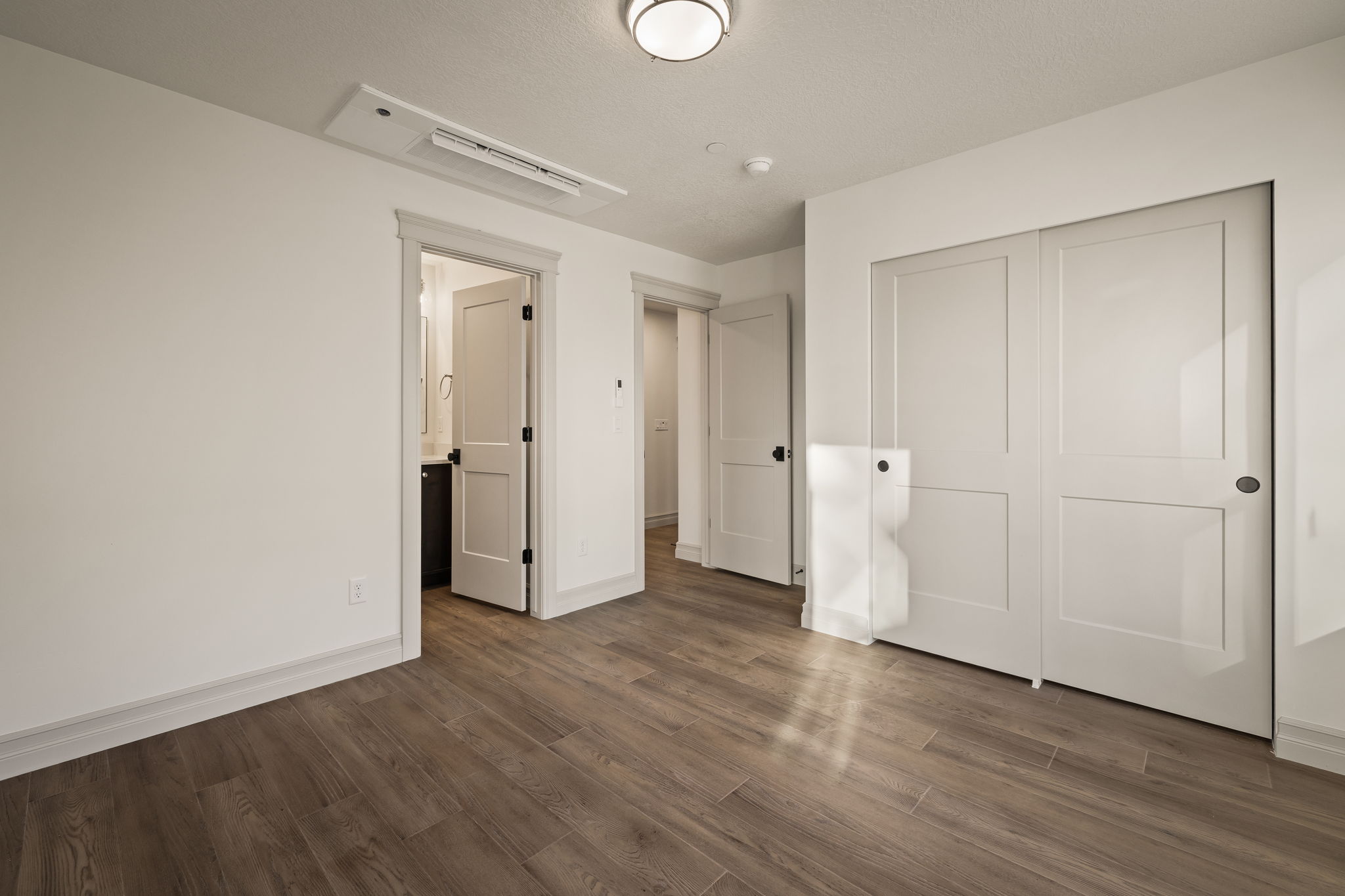 Pictures of an exterior unit -Unfurnished bedroom with dark wood-style flooring, a closet, connected bathroom, and a textured ceiling