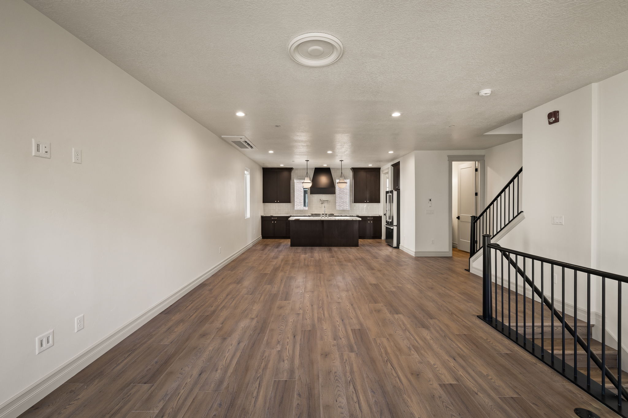 Pictures of an exterior unit -Unfurnished living room featuring dark wood-type flooring, recessed lighting, and a textured ceiling