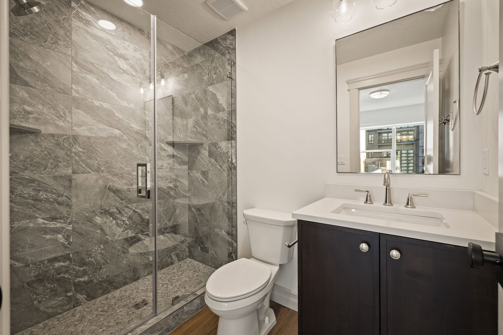 Photos of an exterior unit with the same finishes -Bathroom with vanity, a marble finish shower, and a textured ceiling