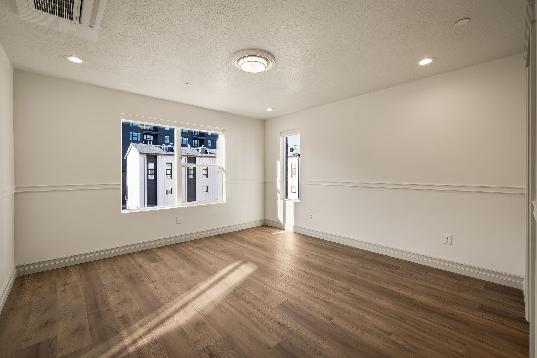 Photos of an exterior unit with the same finishes -Empty room featuring a textured ceiling, recessed lighting, and dark wood-style flooring