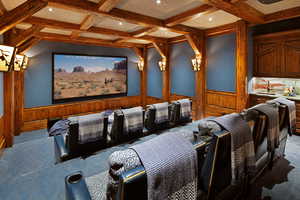 Carpeted cinema featuring coffered ceiling, wainscoting, and wood walls