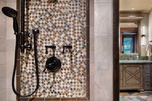 Full bath with vanity, tiled shower, recessed lighting, and light stone finish floors
