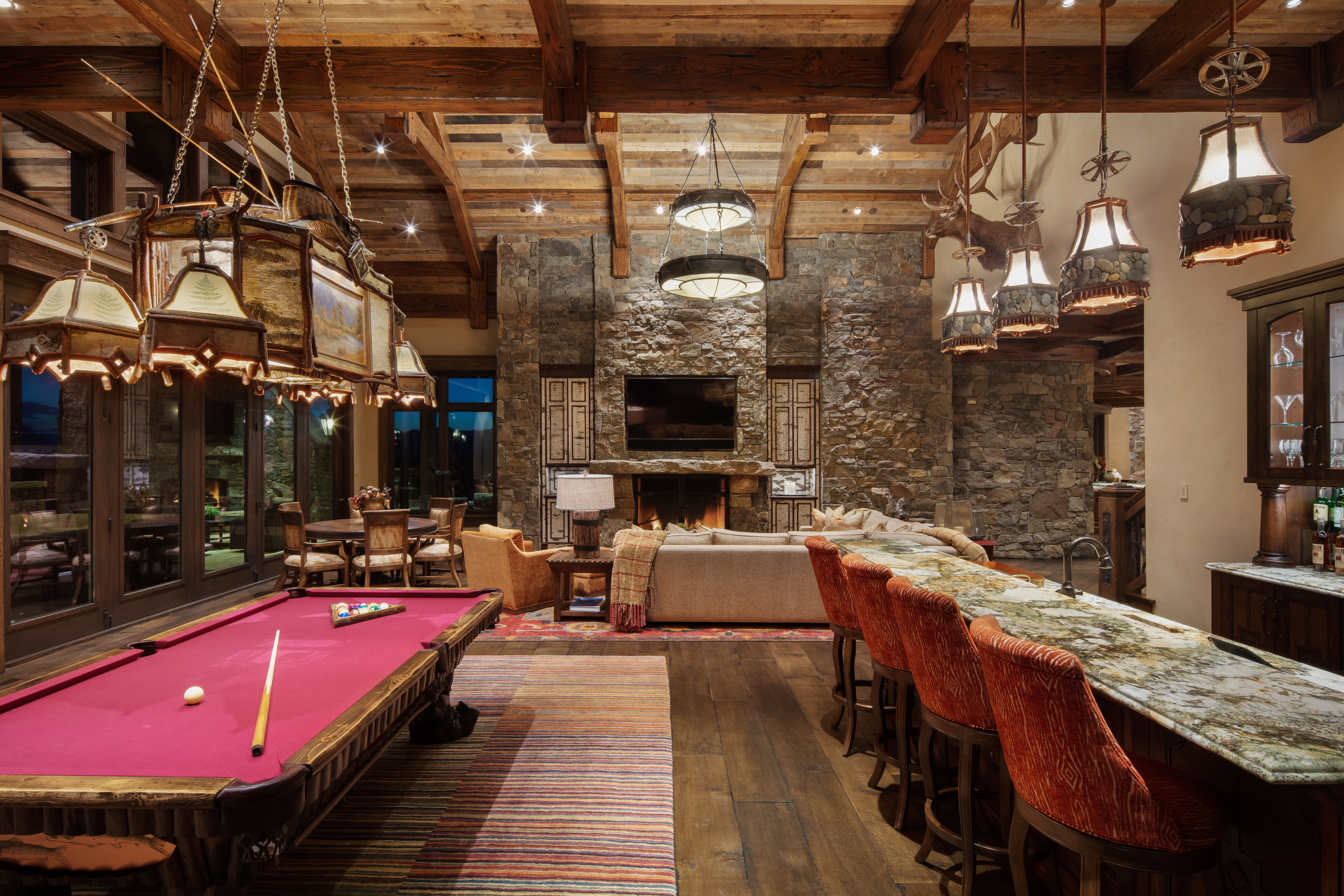 Playroom featuring dark wood finished floors, billiards table, a high wood beamed ceiling, a fireplace, and bar with sink