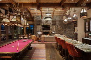 Playroom featuring dark wood finished floors, billiards table, a high wood beamed ceiling, a fireplace, and bar with sink