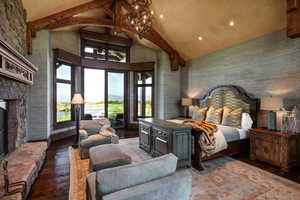 Bedroom with wood-type flooring and a stone fireplace