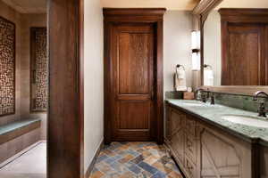 Bathroom with double vanity and dark stone finish floors