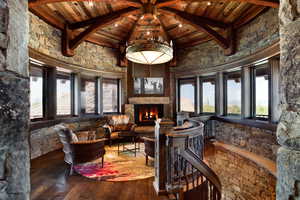 Sitting room featuring wood-type flooring, a high wood beamed ceiling, and a fireplace