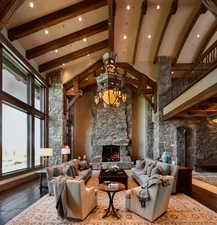 Living area with dark wood-style flooring, a stone fireplace, lofted ceiling, and recessed lighting