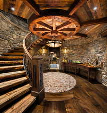 Wine room featuring dark wood-style flooring and a wooden ceiling with exposed beams