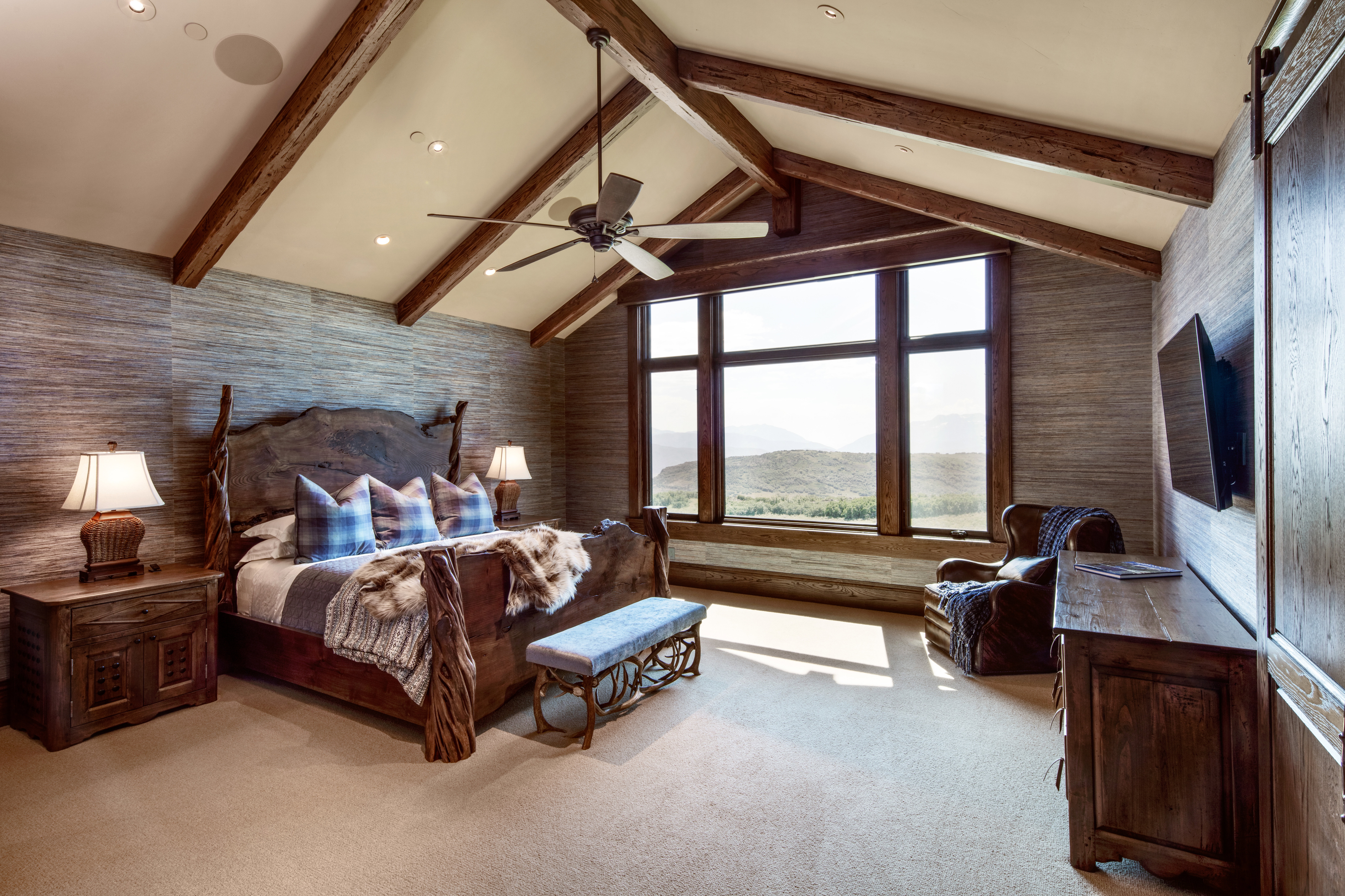 Bedroom with light carpet, wallpapered walls, ceiling fan, and beam ceiling