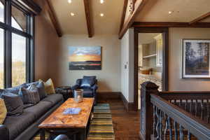 Living room featuring dark wood finished floors, beam ceiling, and recessed lighting