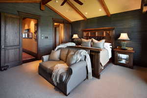Bedroom featuring a barn door, light colored carpet, wallpapered walls, and beam ceiling