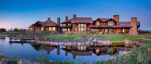Back of property with a chimney, a water view, and a yard