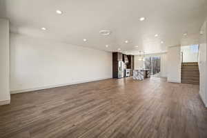 Unfurnished living room with dark wood-style flooring and suspended lighting